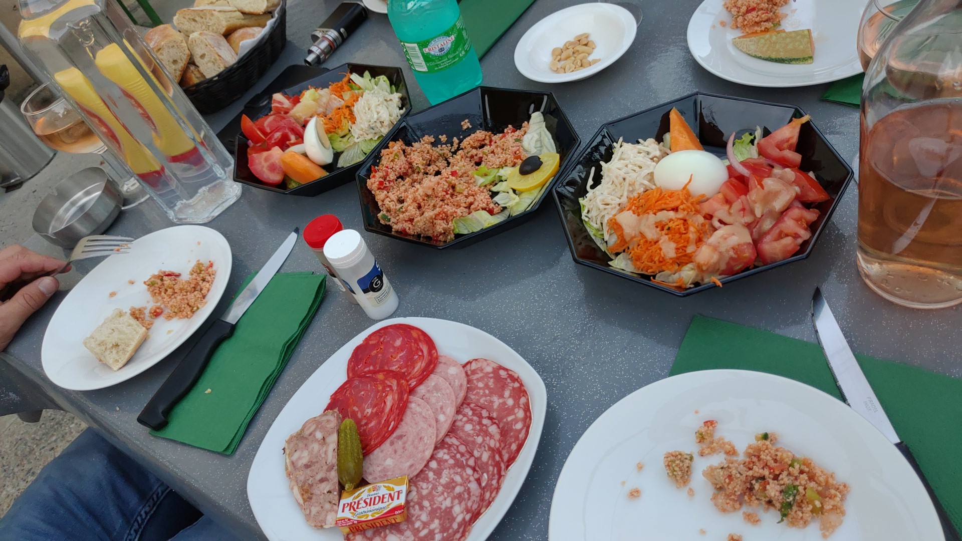 Une grande table dressée de salades, charcuteries et pain