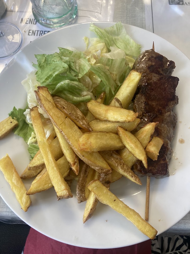 Une brochette de viande avec frites maison et salade