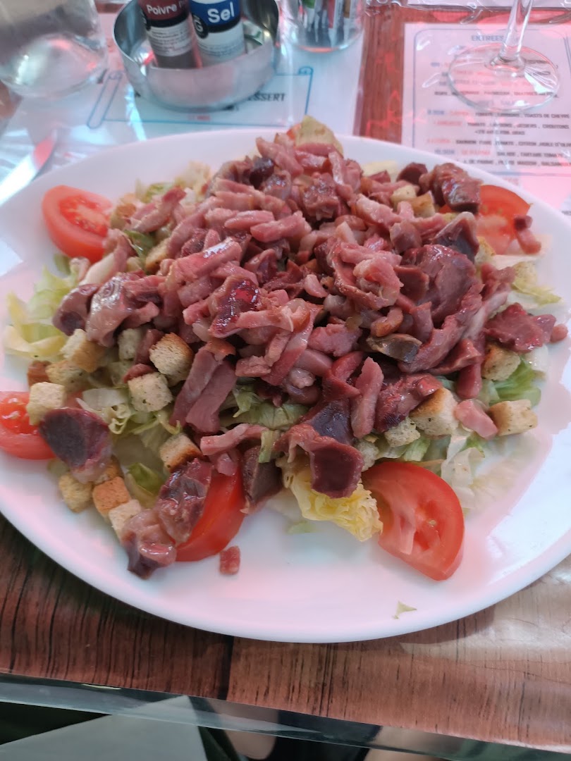 Une grande salade garnie de tomates, croûtons et viande